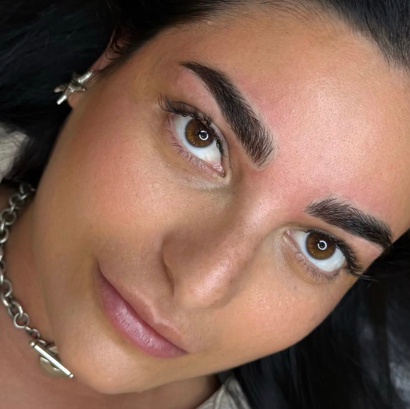 Brows after a permanent makeup treatment, photographed close up with the face turned to the light.