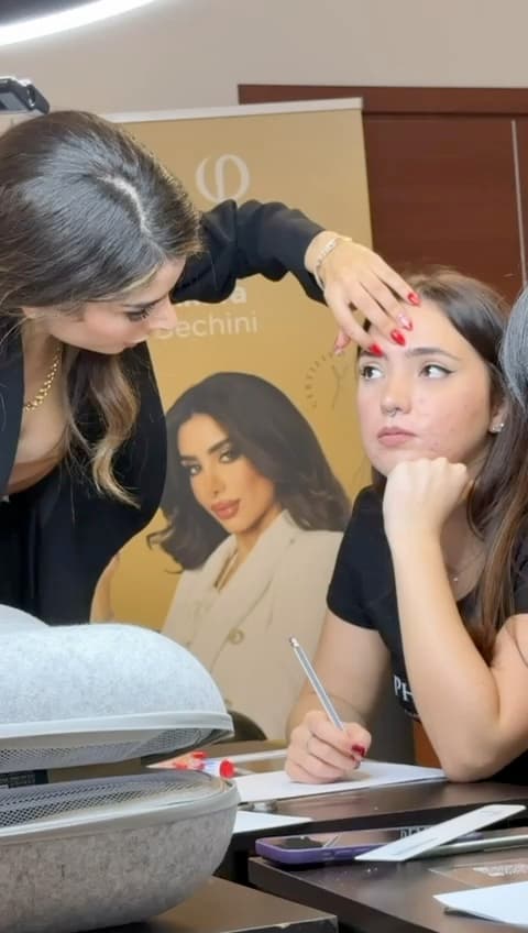 Amira Bechini measuring a model's brow with calipers during a live demonstration, the marker still in her other hand.
